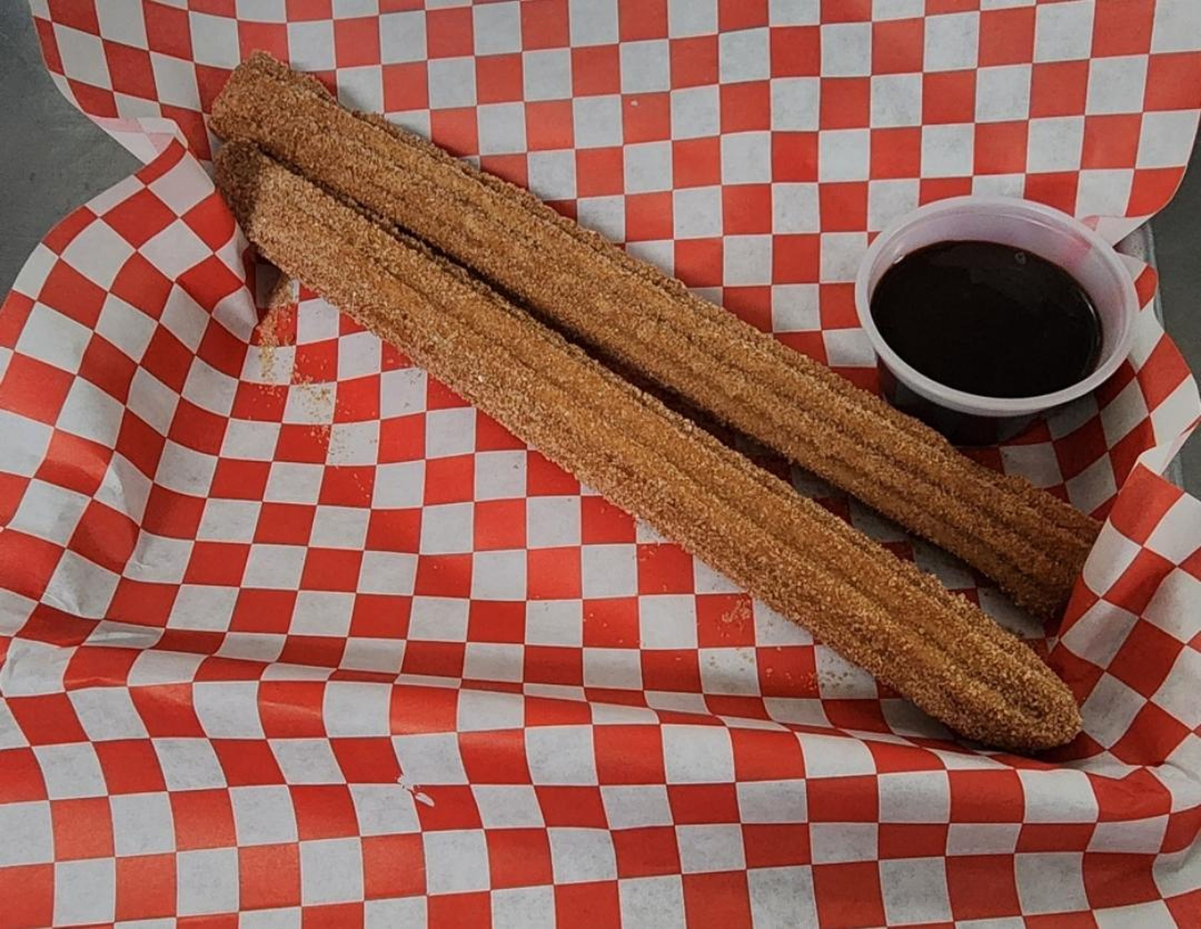 2 churros with chocolate syrup dip.